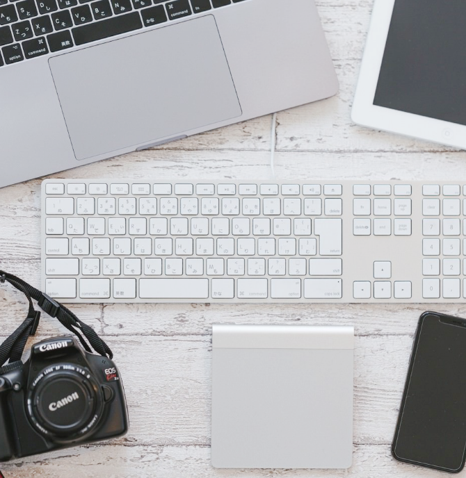 机の上にPCのキーボードやカメラなどが映った写真